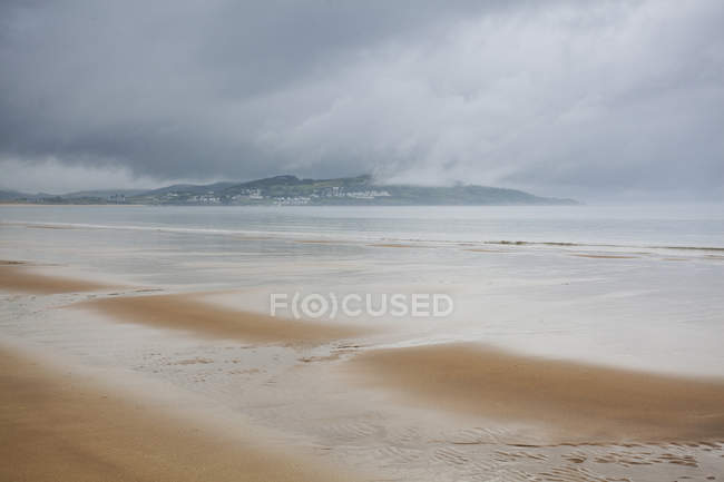 Sandy beach with wavy water  during daytime — Stock Photo
