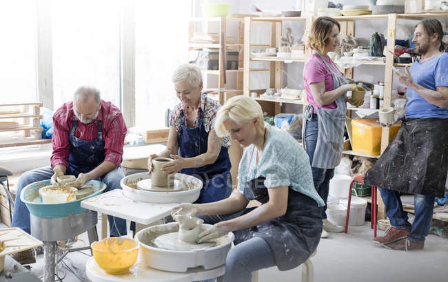 Mature students using pottery wheels in studio — Stock Photo