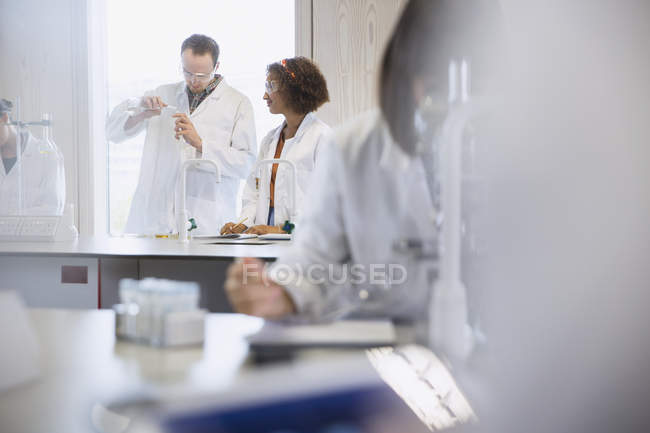 Estudiantes universitarios realizando experimentos científicos en clase de laboratorio de ciencias - foto de stock