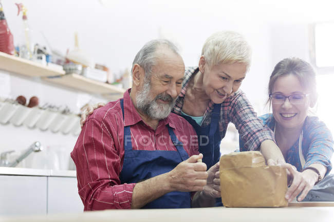 Friends cutting block of clay in pottery studio — Stock Photo