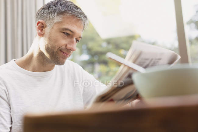 Man reading newspaper at breakfast — Stock Photo