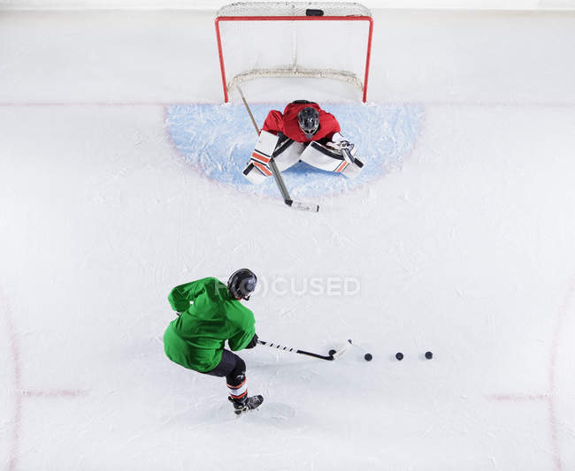 Joueur de hockey vue aérienne s'entraînant avec le gardien tirant la rondelle au filet de but — Photo de stock