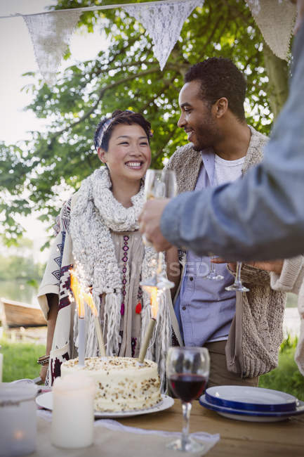 Amigos celebrando con pastel de cumpleaños en la mesa del patio - foto de stock