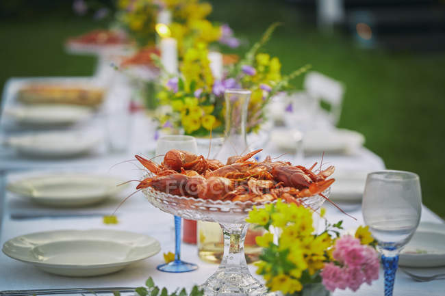 Crayfish in glass bowl on elegant garden party table — Stock Photo