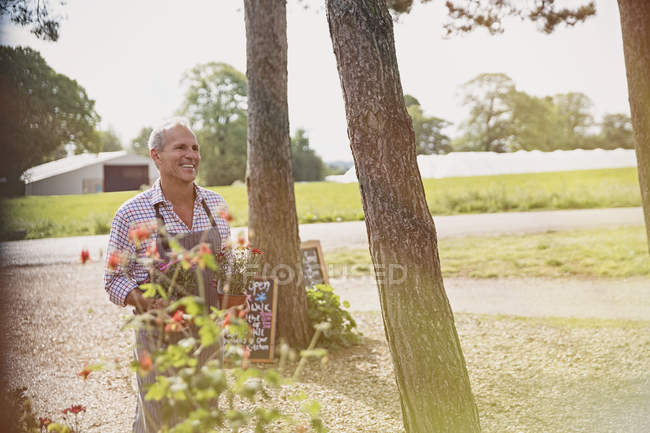 Улыбающийся работник питомника с цветами — стоковое фото