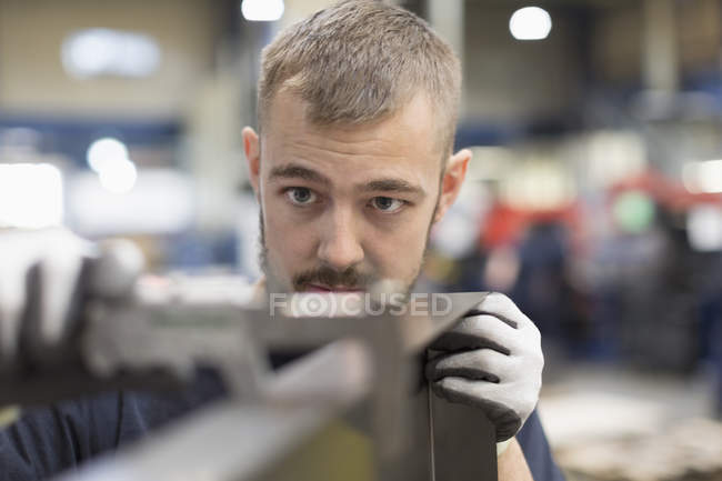 Focused worker examining part in steel factory — Stock Photo