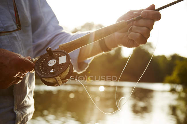 Close up senior man fly fishing at sunny river — Stock Photo