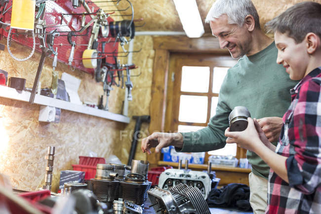 Father and son examining car parts in auto repair shop — Stock Photo