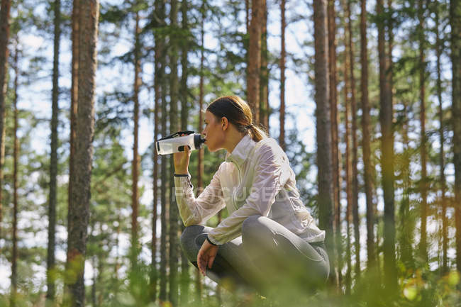 Бегун отдыхает бутылку питьевой воды в лесу — стоковое фото