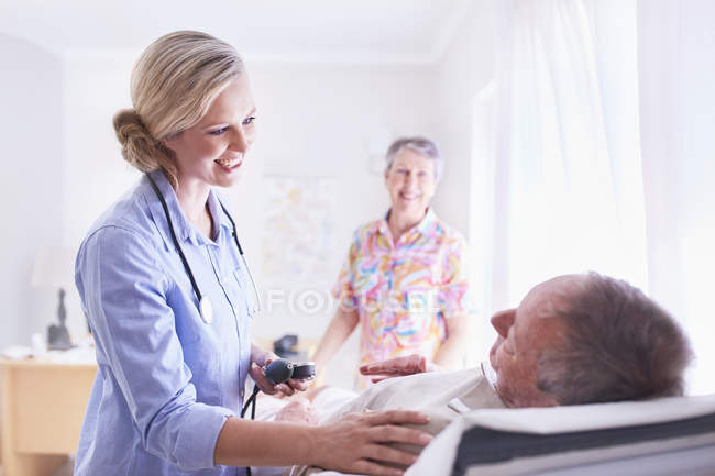 Médico revisando la presión arterial del hombre mayor en la sala de examen - foto de stock