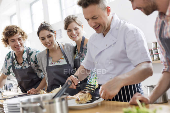Студенты наблюдают за преподавателем шеф-повара на кухне кулинарного класса — стоковое фото