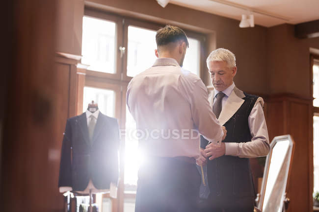 Кравець підходить бізнесмен для костюма в магазині чоловічого одягу — стокове фото