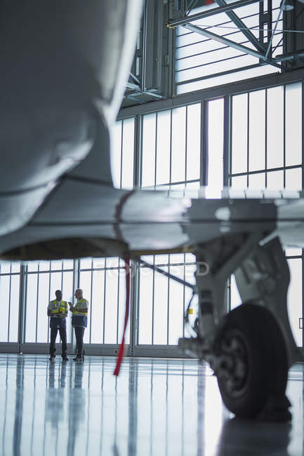 Operai di terra addetti al controllo del traffico aereo che parlano nell'hangar degli aerei — Foto stock
