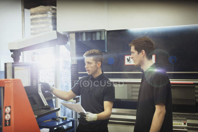 Arbeiter bildet Auszubildenden im Maschinenbedienfeld in Stahlwerk aus — Stockfoto