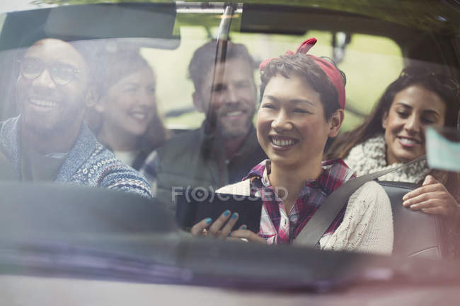 Amigos sonrientes usando GPS en el teléfono inteligente montando en el coche - foto de stock