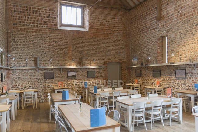 Mesas en restaurante vacante con paredes de ladrillo y techo abovedado - foto de stock