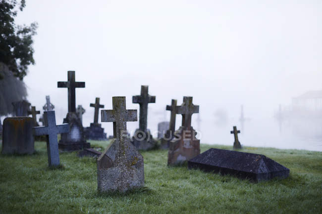 Crosses on gravestones in ethereal foggy cemetery — Stock Photo