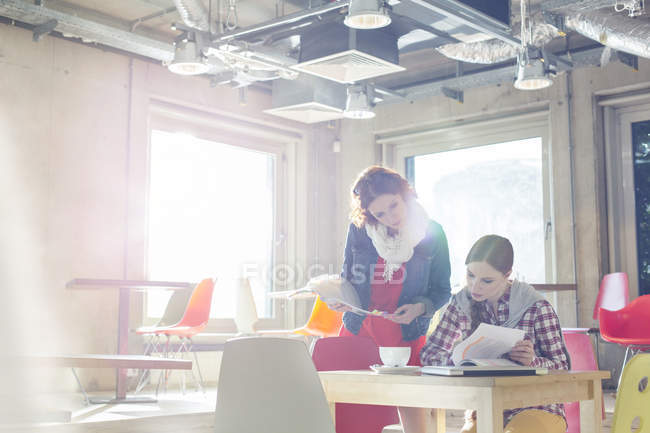 Creative businesswomen reviewing document edits in sunny office — Stock Photo