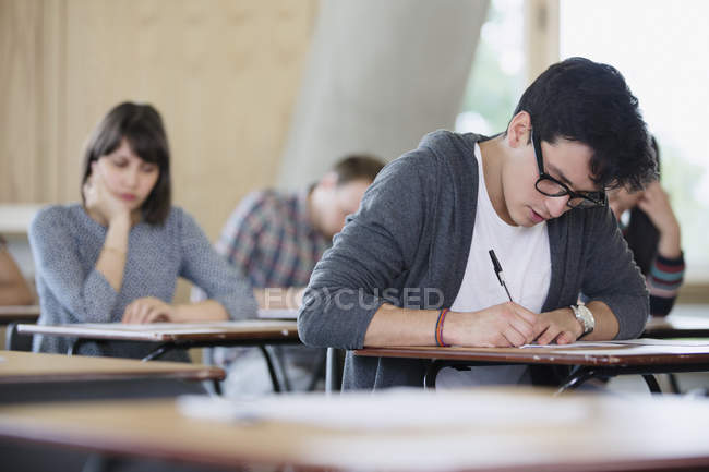 Fokussierte männliche College-Student macht Test am Schreibtisch im Klassenzimmer — Stockfoto