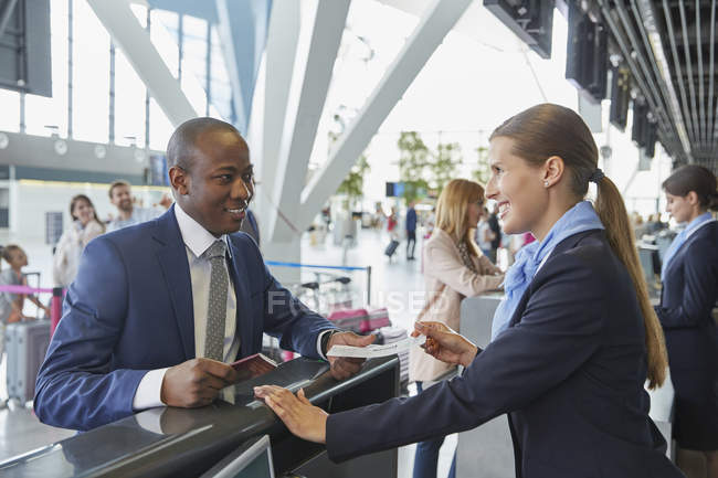 Kundendienstmitarbeiter hilft Geschäftsmann am Flughafen-Check-in-Schalter — Stockfoto