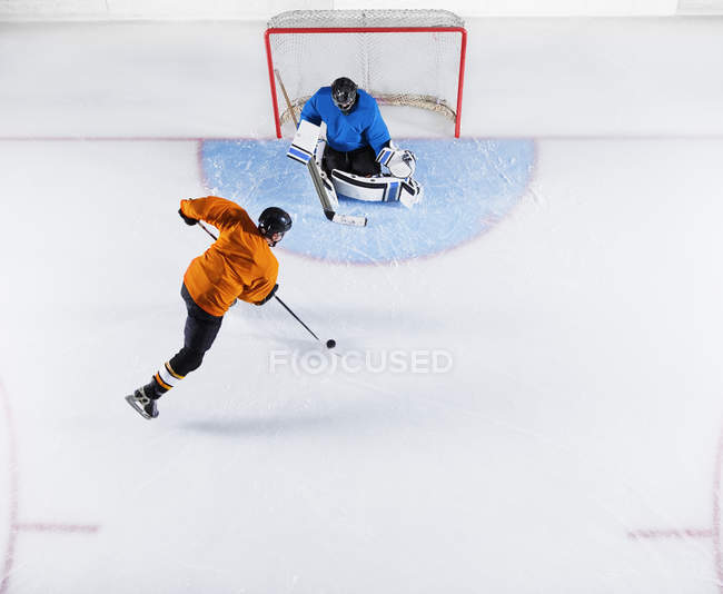 Jugador de hockey disparando el disco en la red de gol - foto de stock