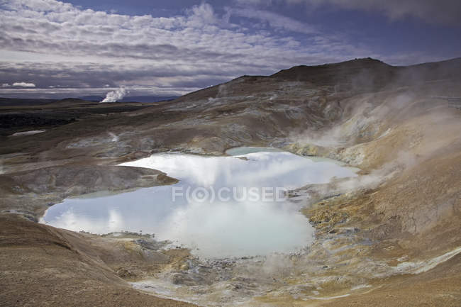 Steaming pond water at rock — Stock Photo