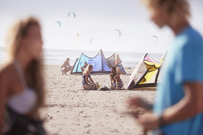 Pessoas com equipamento de kiteboarding na praia ensolarada — Fotografia de Stock