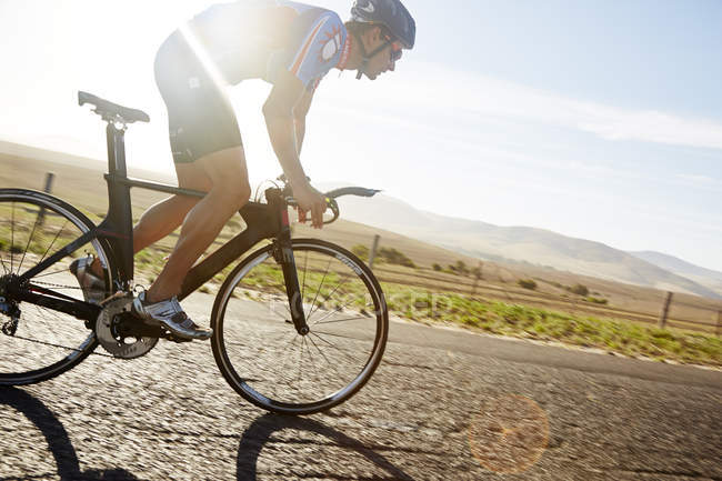 Cycliste triathlète homme cycliste sur route rurale ensoleillée au lever du soleil — Photo de stock
