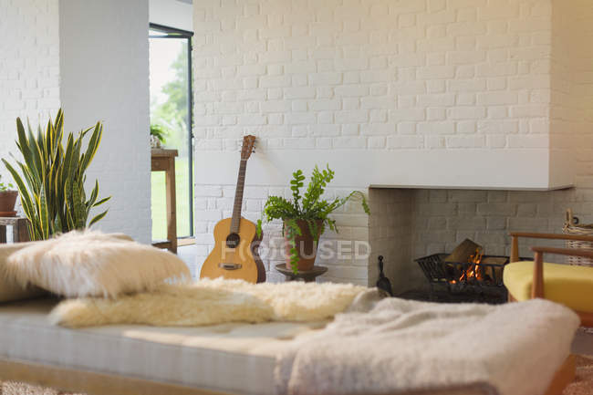Guitar leaning near fireplace behind chaise in living room — Stock Photo
