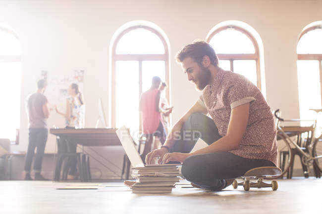 Casual businessman working at laptop from skateboard — Stock Photo