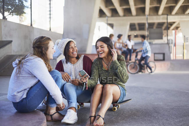 Chicas adolescentes en mensajes de texto de skate y pasar el rato en el parque de skate - foto de stock