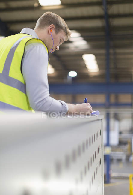 Supervisor schreibt auf Klemmbrett in Stahlfabrik — Stockfoto