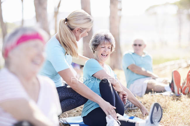 Yoga instructor guiding senior woman in sunny park — Stock Photo