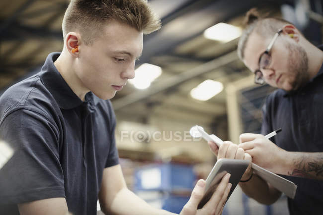 Workers with paperwork and digital tablet in steel factory — Stock Photo