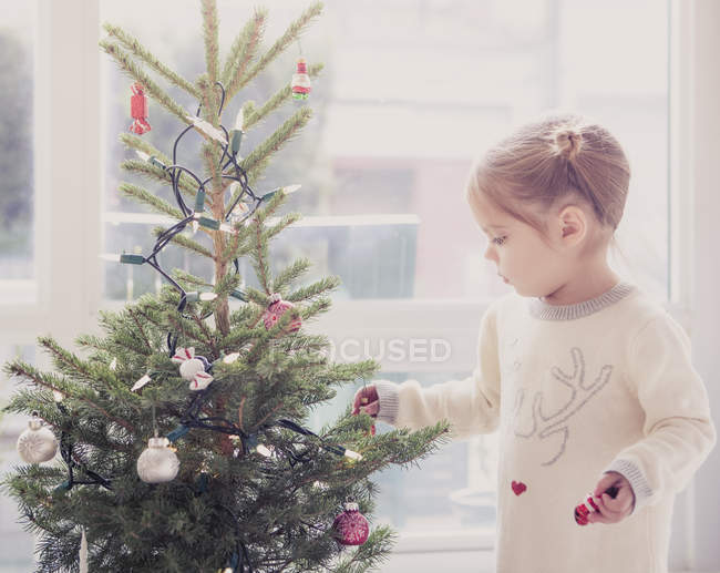 Girl decorating small Christmas tree — Stock Photo