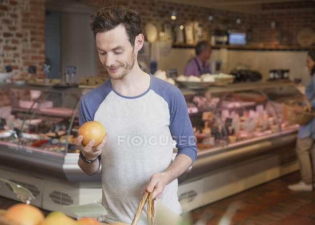 Uomo esaminando pompelmo nel mercato — Foto stock