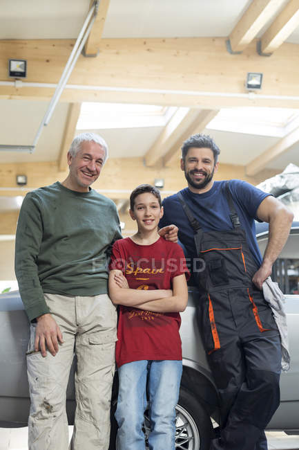 Retratos sonriendo familia mecánica multi-generación en taller de reparación de automóviles - foto de stock