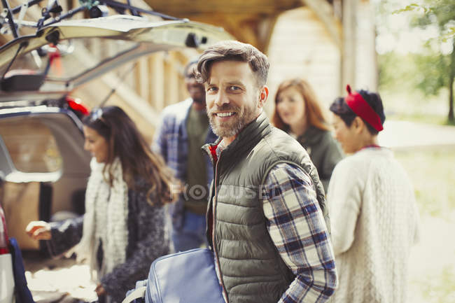 Retrato sorridente homem com amigos descarregar carro — Fotografia de Stock