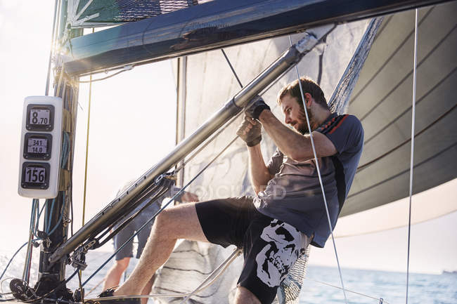 Young man adjusting sailing equipment — Stock Photo