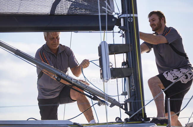 Caucasian men adjusting sailing equipment — Stock Photo
