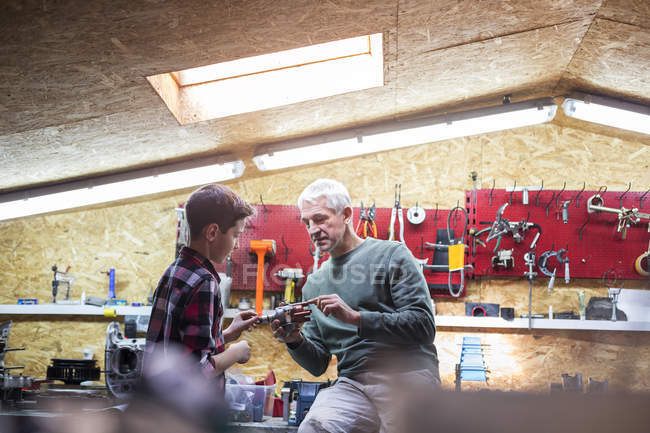 Father explaining tool to son in auto repair shop — Stock Photo