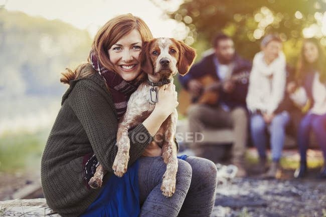Retrato sorridente mulher abraçando cão no acampamento com amigos — Fotografia de Stock