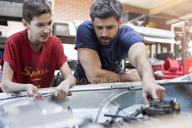 Батько і син ремонтують автомобільний двигун — стокове фото