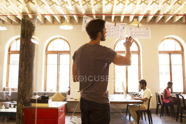 Casual businessman reviewing hanging diagrams in office — Stock Photo
