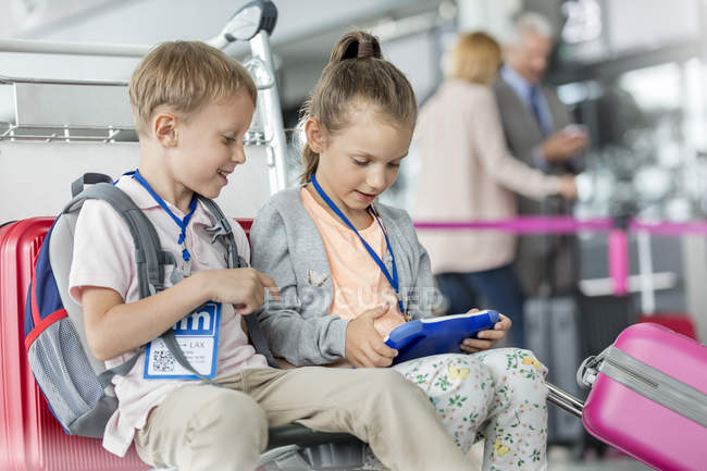 Irmão e irmã usando tablet digital na área de partida do aeroporto — Fotografia de Stock