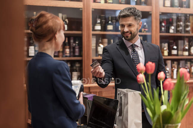 Бізнесмен платить клерку в лічильнику магазину алкоголю — стокове фото