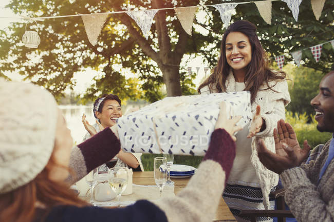Woman receiving birthday gift at garden party — Stock Photo