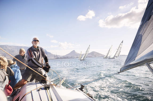 Uomo regolazione barca a vela sartiame sull'oceano soleggiato — Foto stock