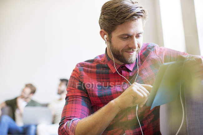 Casual businessman with headphones and digital tablet in office — Stock Photo