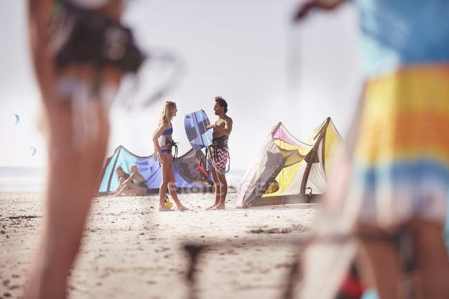 People with kiteboarding equipment talking on sunny beach — Stock Photo